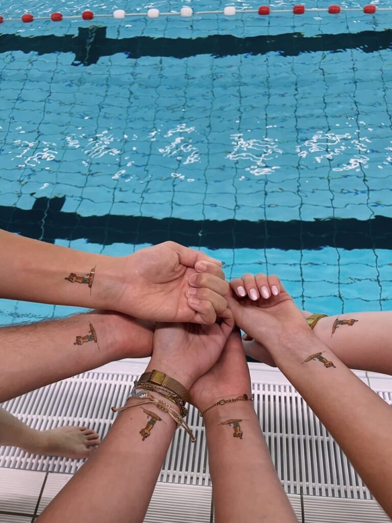 Six poignets au bord d'une piscine, chacun avec le même tatouage éphémère personnalisé