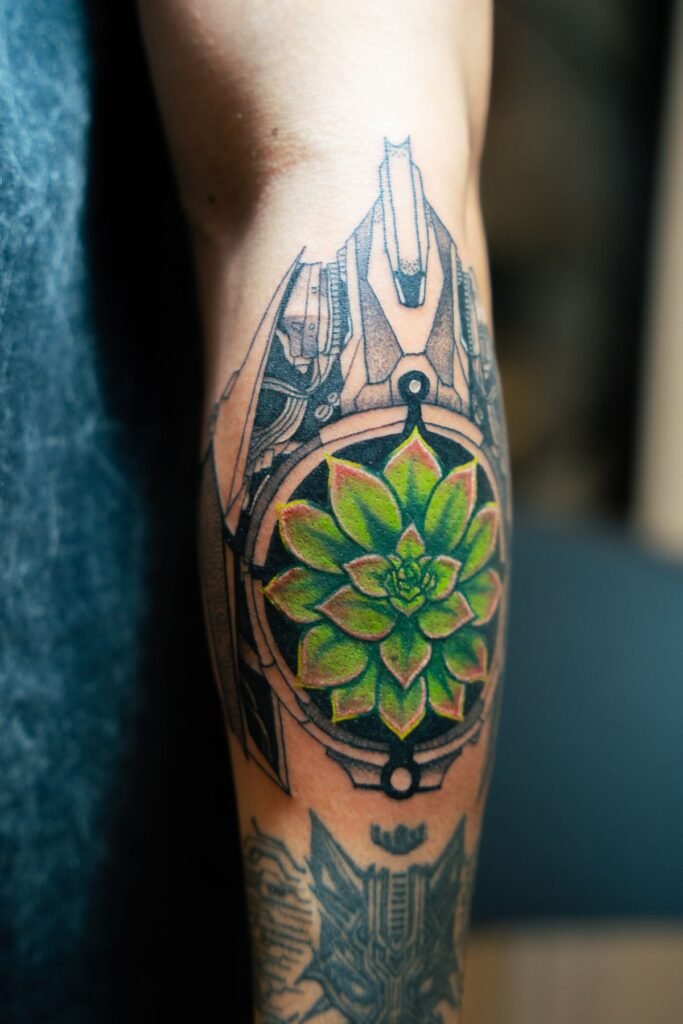 Tatouage mandala géométrique avec une fleur verte au centre, sur un mollet